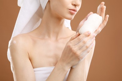 Photo of Woman with soap bar on brown background, closeup