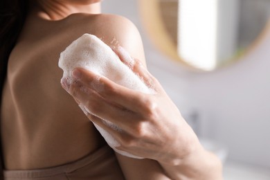 Photo of Woman washing body with soap bar in bathroom, closeup