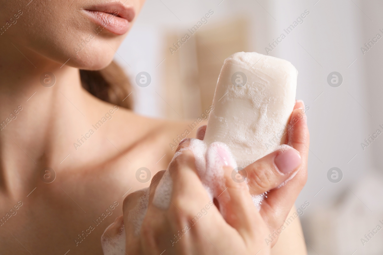 Woman with foaming soap bar indoors, closeup Photo of Woman with foaming soap bar indoors, closeup