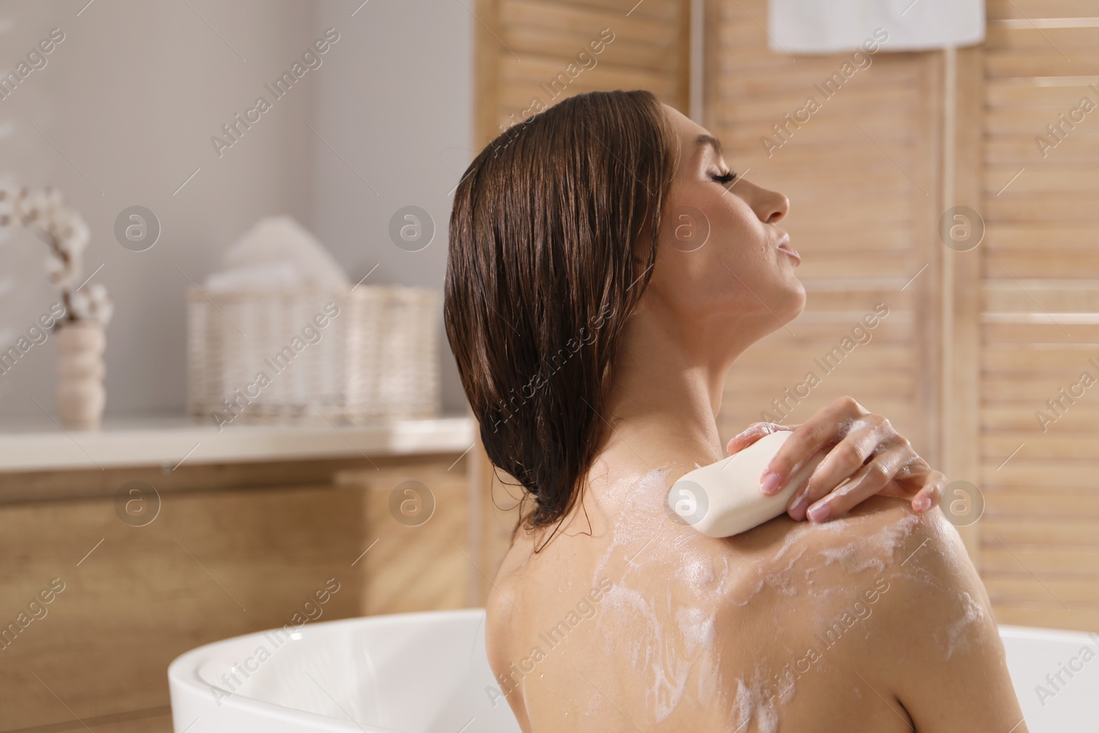 Woman washing body with soap bar in bathroom. Space for text Photo of Woman washing body with soap bar in bathroom. Space for text