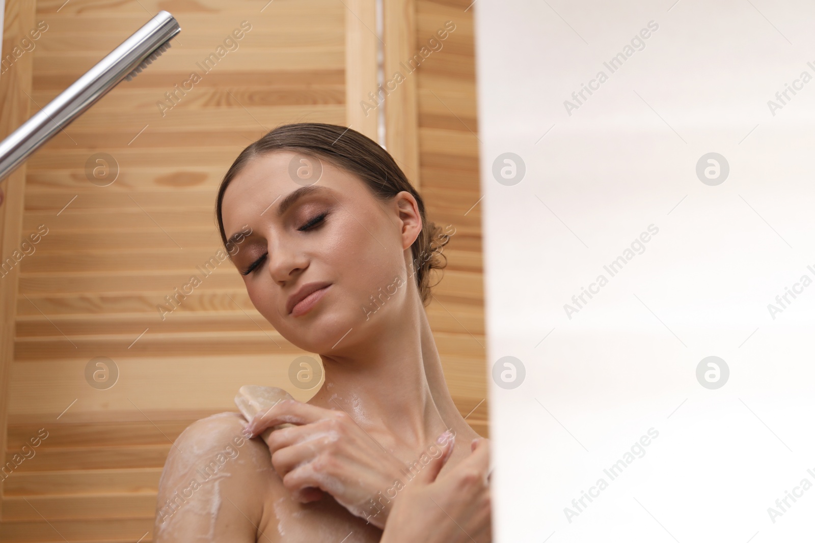Photo of Woman washing body with soap bar indoors. Space for text