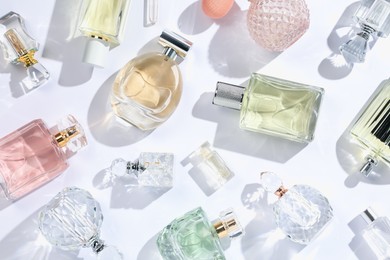 Photo of Luxury perfumes and beautiful lilac flowers on white background, flat lay