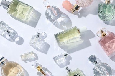 Photo of Luxury perfumes and beautiful lilac flowers on white background, flat lay
