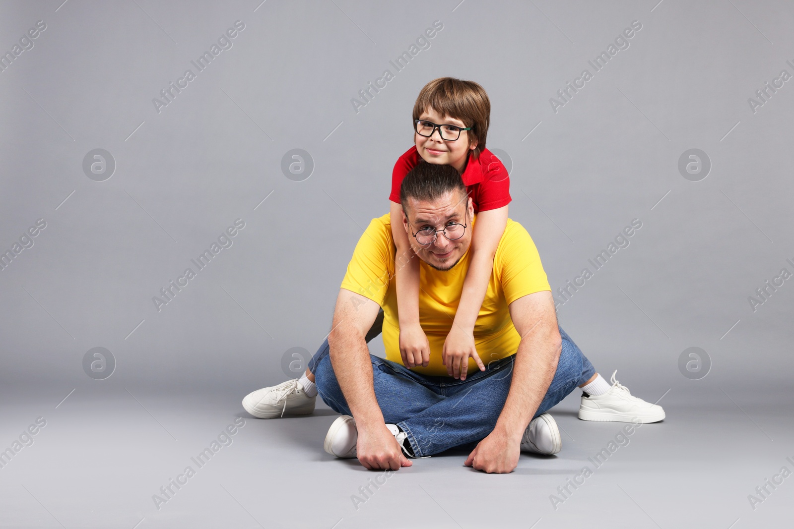 Father and his son on grey background, space for text Photo of Father and his son on grey background, space for text