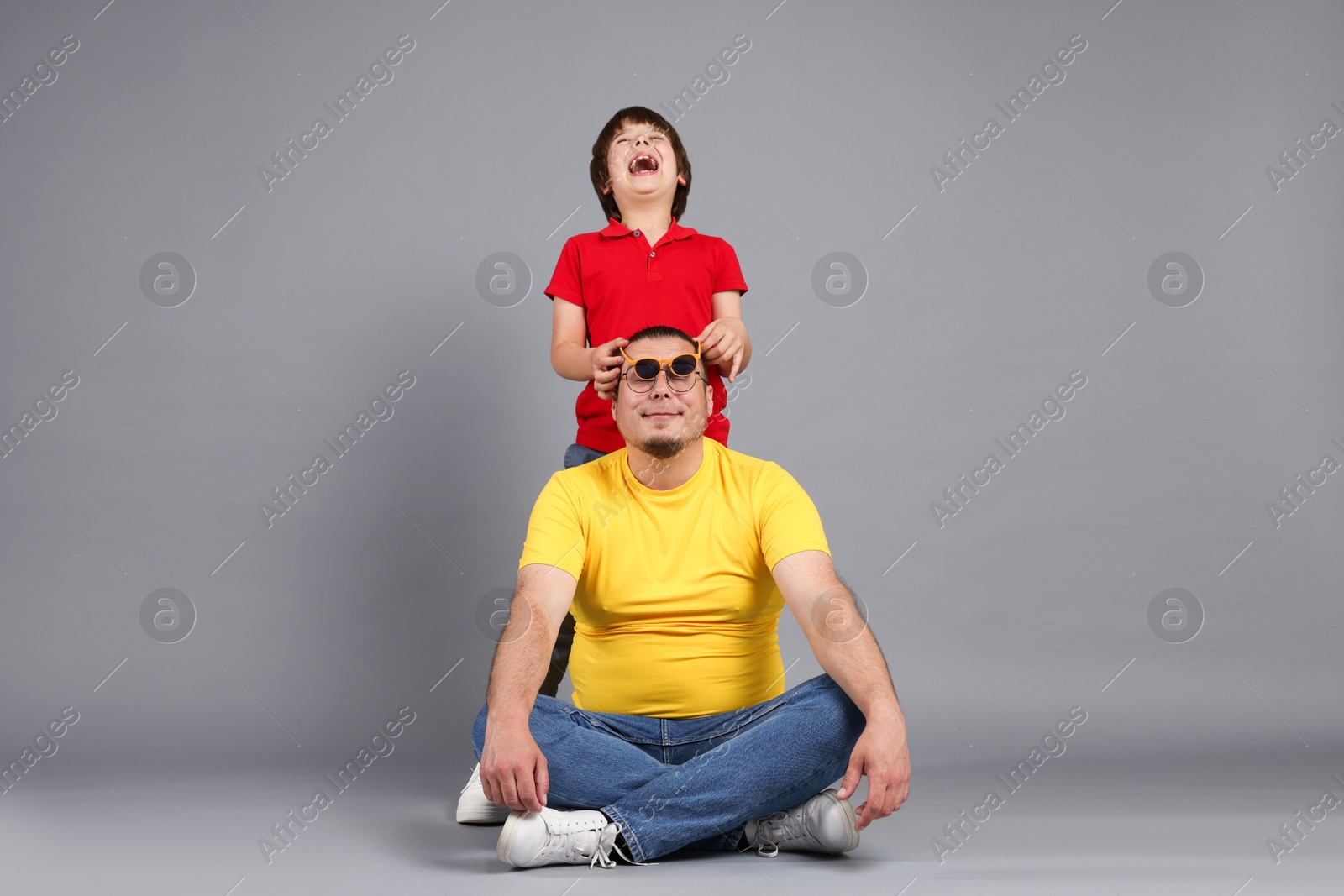 Father and his son on grey background Photo of Father and his son on grey background