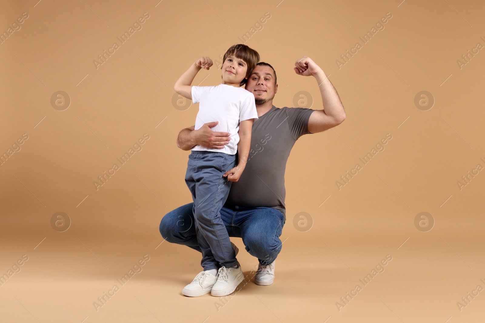 Father and his son on beige background Photo of Father and his son on beige background