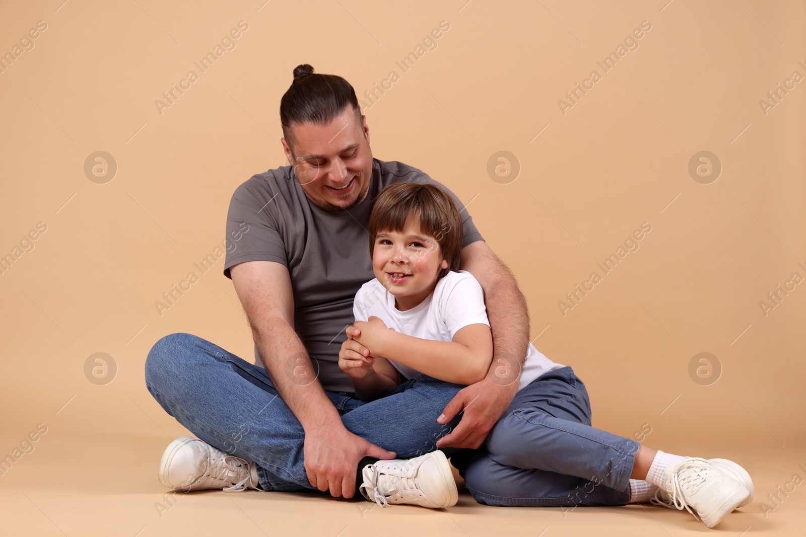 Father and his son on beige background Photo of Father and his son on beige background