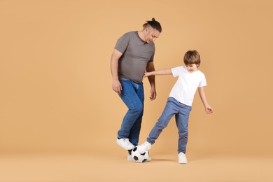 Photo of Father and his son playing football on beige background
