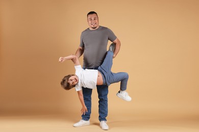 Photo of Father and his son having fun together on beige background
