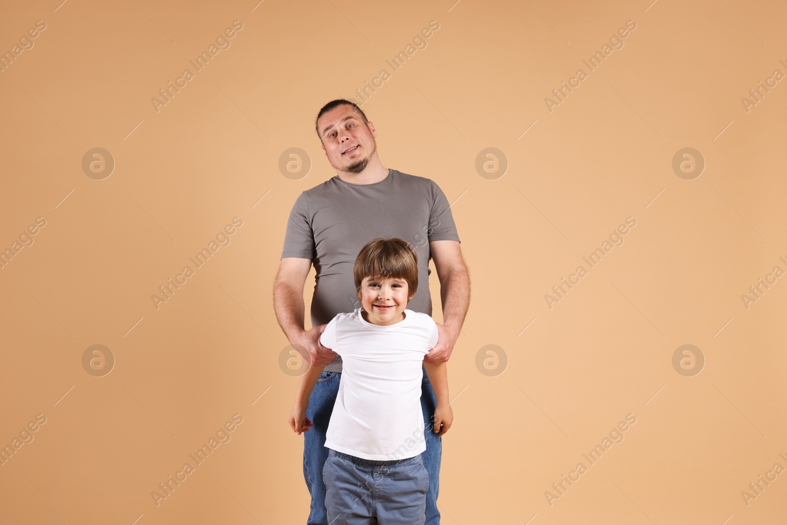 Father and his son on beige background Photo of Father and his son on beige background