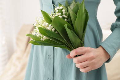 Photo of Woman with beautiful lilies of the valley flowers indoors, closeup