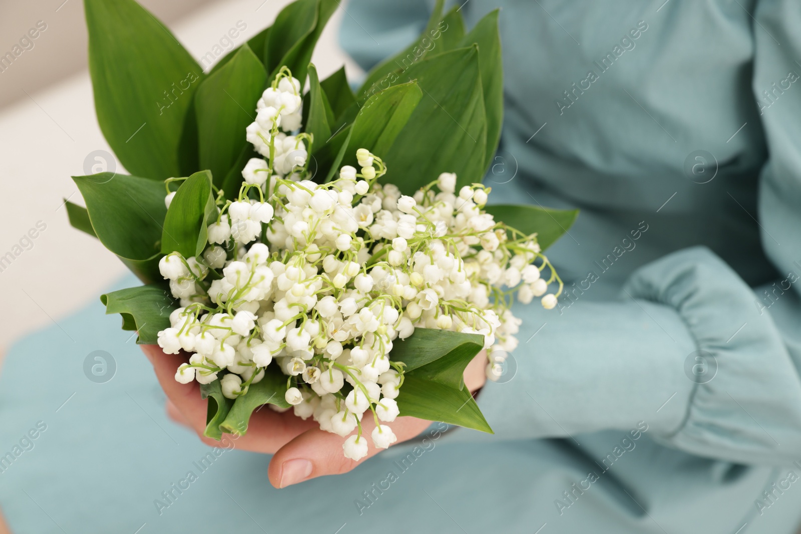Woman with beautiful lilies of the valley flowers indoors, closeup Photo of Woman with beautiful lilies of the valley flowers indoors, closeup