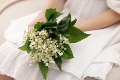 Photo of Woman with beautiful lilies of the valley flowers indoors, closeup