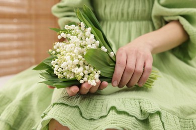 Photo of Woman with beautiful lilies of the valley flowers indoors, closeup