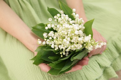 Photo of Woman with beautiful lilies of the valley flowers indoors, closeup