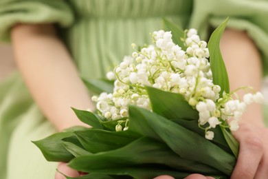 Photo of Woman with beautiful lilies of the valley flowers indoors, closeup