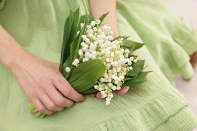 Photo of Woman with beautiful lilies of the valley flowers indoors, closeup