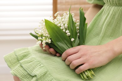 Photo of Woman with beautiful lilies of the valley flowers indoors, closeup