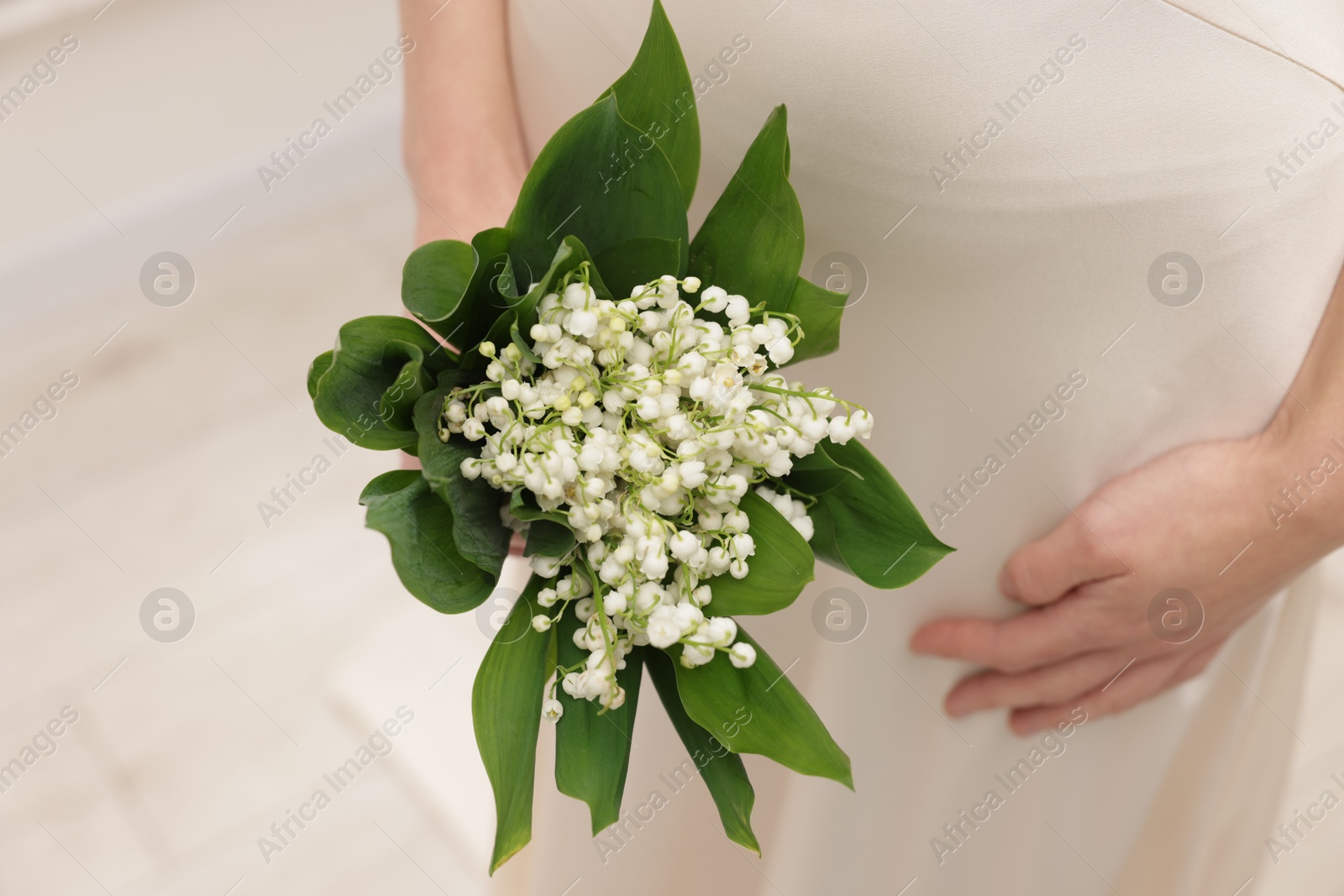 Woman with beautiful lilies of the valley flowers indoors, closeup Photo of Woman with beautiful lilies of the valley flowers indoors, closeup