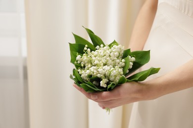 Photo of Woman with beautiful lilies of the valley flowers indoors, closeup