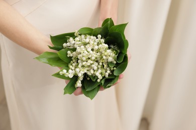 Photo of Woman with beautiful lilies of the valley flowers indoors, closeup