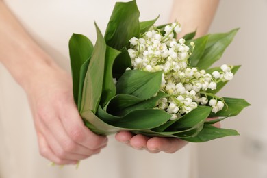 Photo of Woman with beautiful lilies of the valley flowers indoors, closeup
