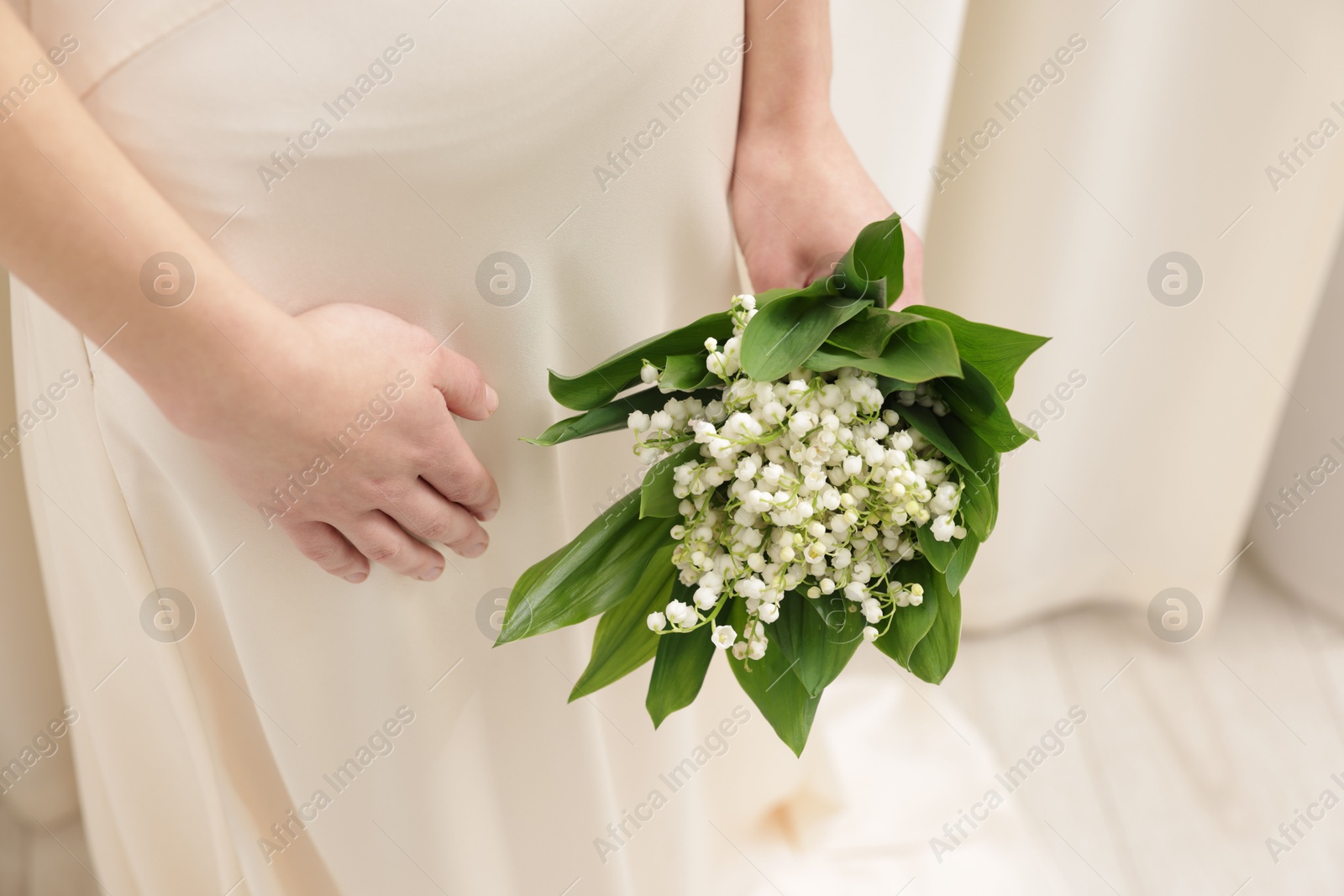 Woman with beautiful lilies of the valley flowers indoors, closeup Photo of Woman with beautiful lilies of the valley flowers indoors, closeup