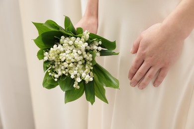 Photo of Woman with beautiful lilies of the valley flowers indoors, closeup