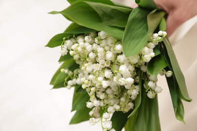 Photo of Woman with beautiful lilies of the valley flowers indoors, closeup