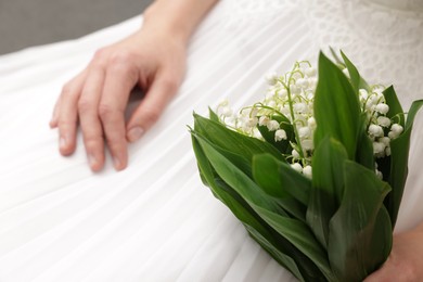 Photo of Bride with bouquet of beautiful lilies of the valley indoors, closeup