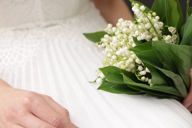 Photo of Bride with bouquet of beautiful lilies of the valley indoors, closeup