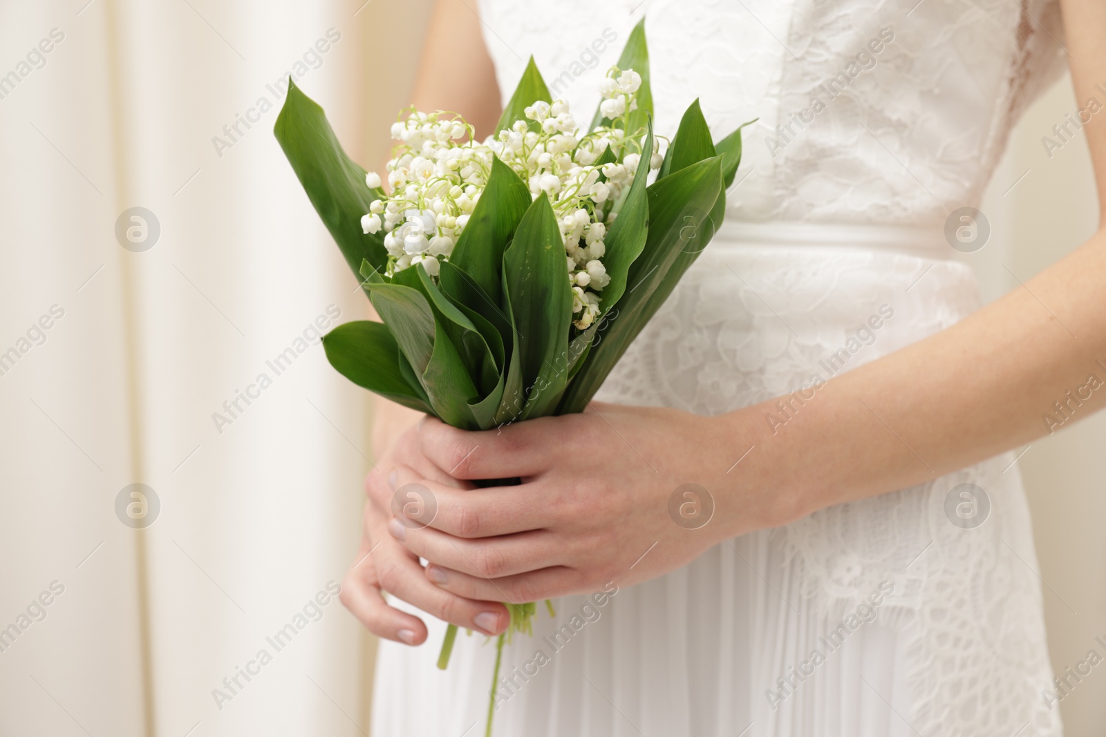 Bride with bouquet of beautiful lilies of the valley indoors, closeup Photo of Bride with bouquet of beautiful lilies of the valley indoors, closeup