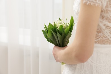 Photo of Bride with bouquet of beautiful lilies of the valley indoors, closeup. Space for text