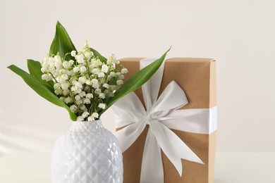 Photo of Beautiful lilies of the valley flowers and gift on white background, closeup
