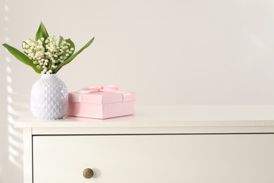 Photo of Beautiful lilies of the valley flowers and gift on white table. Space for text