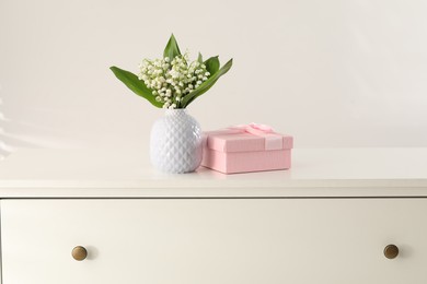 Photo of Beautiful lilies of the valley flowers and gift on white table