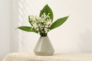 Photo of Beautiful lilies of the valley flowers in vase on table