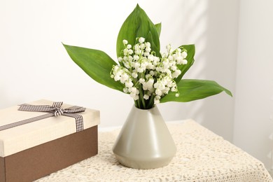 Photo of Beautiful lilies of the valley flowers and gift on table