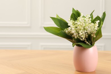 Photo of Beautiful lilies of the valley flowers in vase on wooden table. Space for text