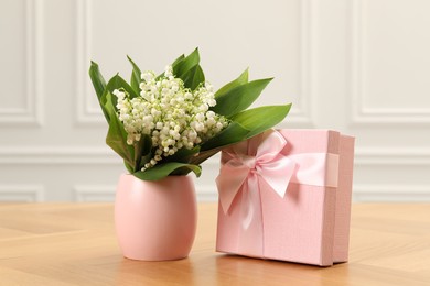 Photo of Beautiful lilies of the valley flowers and gift on wooden table