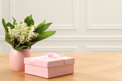 Photo of Beautiful lilies of the valley flowers and gift on wooden table. Space for text