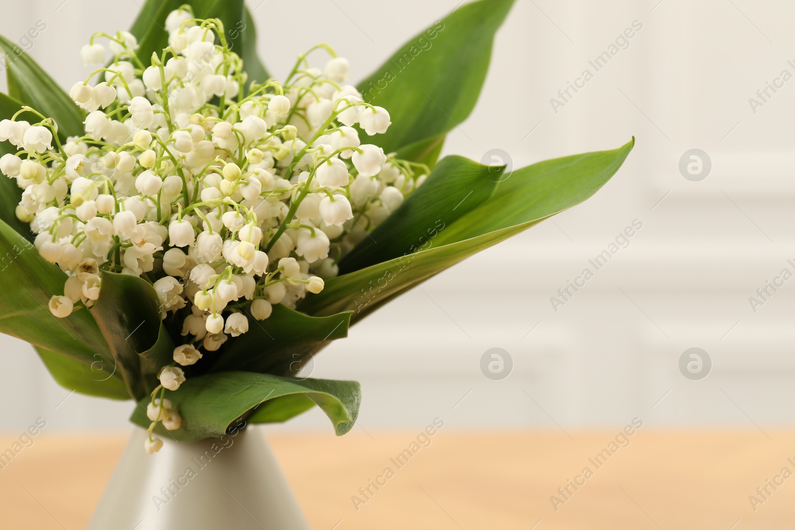 Beautiful lilies of the valley flowers in vase on wooden table, closeup Photo of Beautiful lilies of the valley flowers in vase on wooden table, closeup