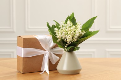 Photo of Beautiful lilies of the valley flowers and gift on wooden table