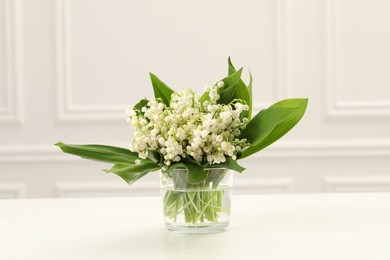 Photo of Beautiful lilies of the valley flowers in vase on white table