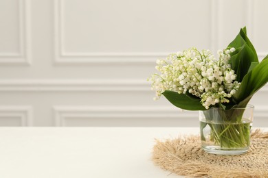 Photo of Beautiful lilies of the valley flowers in vase on white table. Space for text