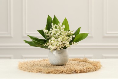 Photo of Beautiful lilies of the valley flowers in vase on white table