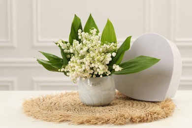 Photo of Beautiful lilies of the valley flowers and heart shaped gift box on white table