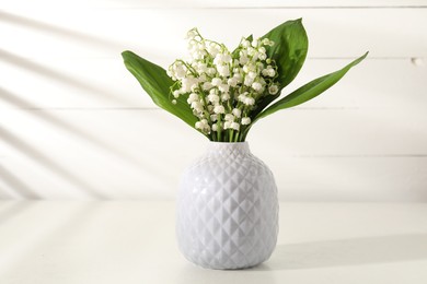 Photo of Beautiful lilies of the valley flowers in vase on white table