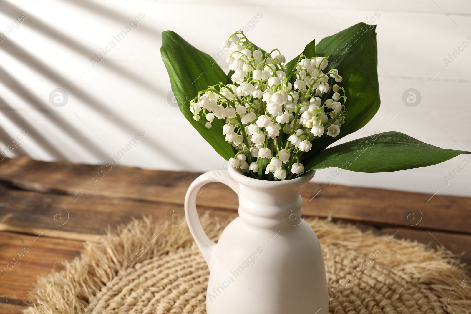 Beautiful lilies of the valley flowers in vase on wooden table, closeup Photo of Beautiful lilies of the valley flowers in vase on wooden table, closeup