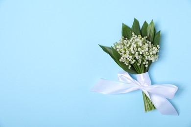 Photo of Beautiful lily-of-the-valley flowers on light blue background, top view. Space for text